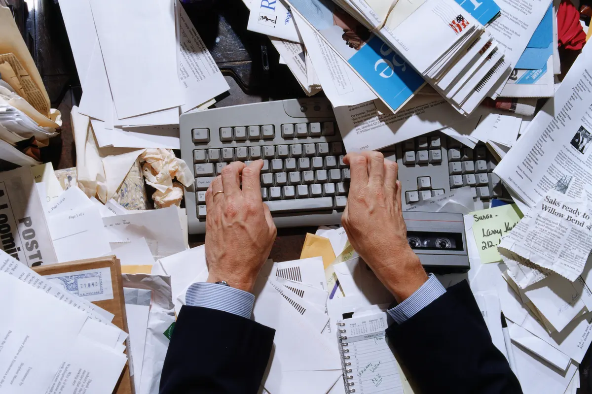Construction business owner overwhelmed with paperwork, invoices, and computer work at desk